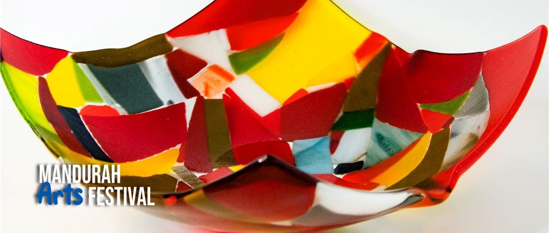 a bowl made up of different pieces of red and yellow coloured glass sits against a white background